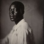 Profile view of Dandelion Eghosa with rugged features, emphasizing contrast and tonal depth in historical photographic presentation. Saltprint from a wetplate collodion glass negative.