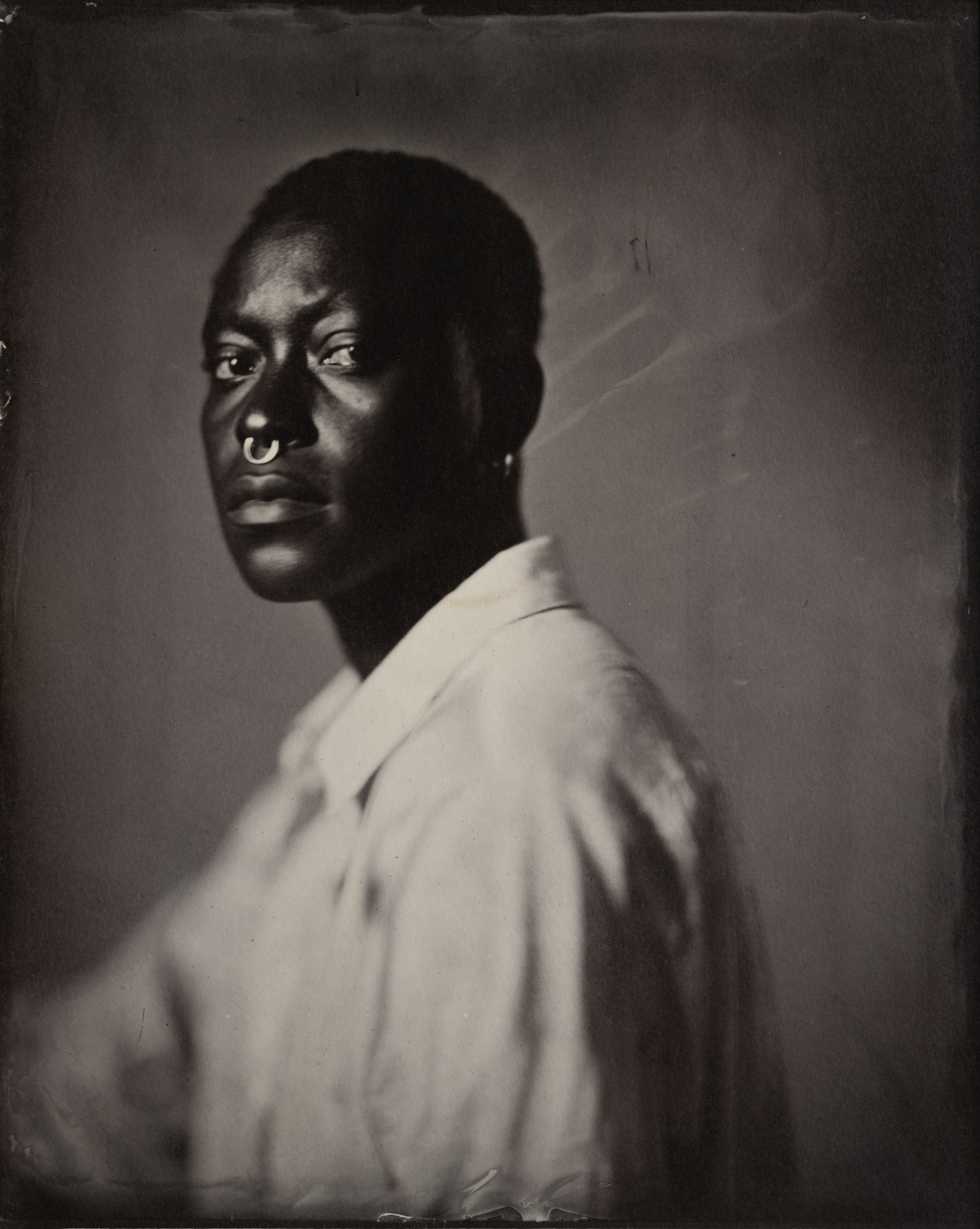 Profile view of Dandelion Eghosa with rugged features, emphasizing contrast and tonal depth in historical photographic presentation. Saltprint from a wetplate collodion glass negative.